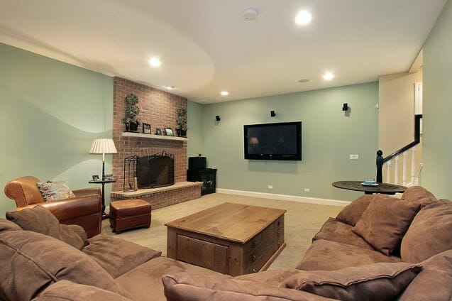 basement with a fireplace, tv on wall, sectional and coffee table